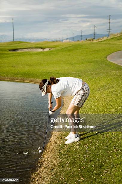 a golfer collecting a golf ball from a water trap - golf collection stock pictures, royalty-free photos & images