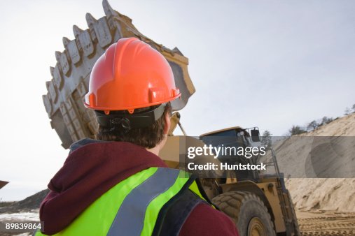 Engineer looking at a front-end loader at a construction site Engineer looking at a front-end loader at a construction site