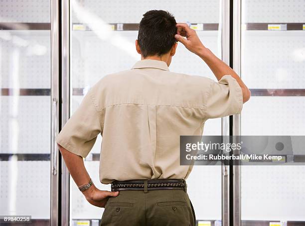 man looking into empty refrigerators at market - scratching head stock pictures, royalty-free photos & images
