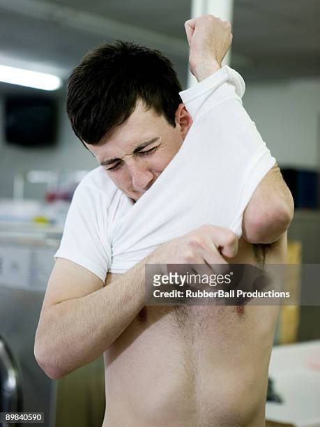 man putting on a shrunken t-shirt - too small stock pictures, royalty-free photos & images