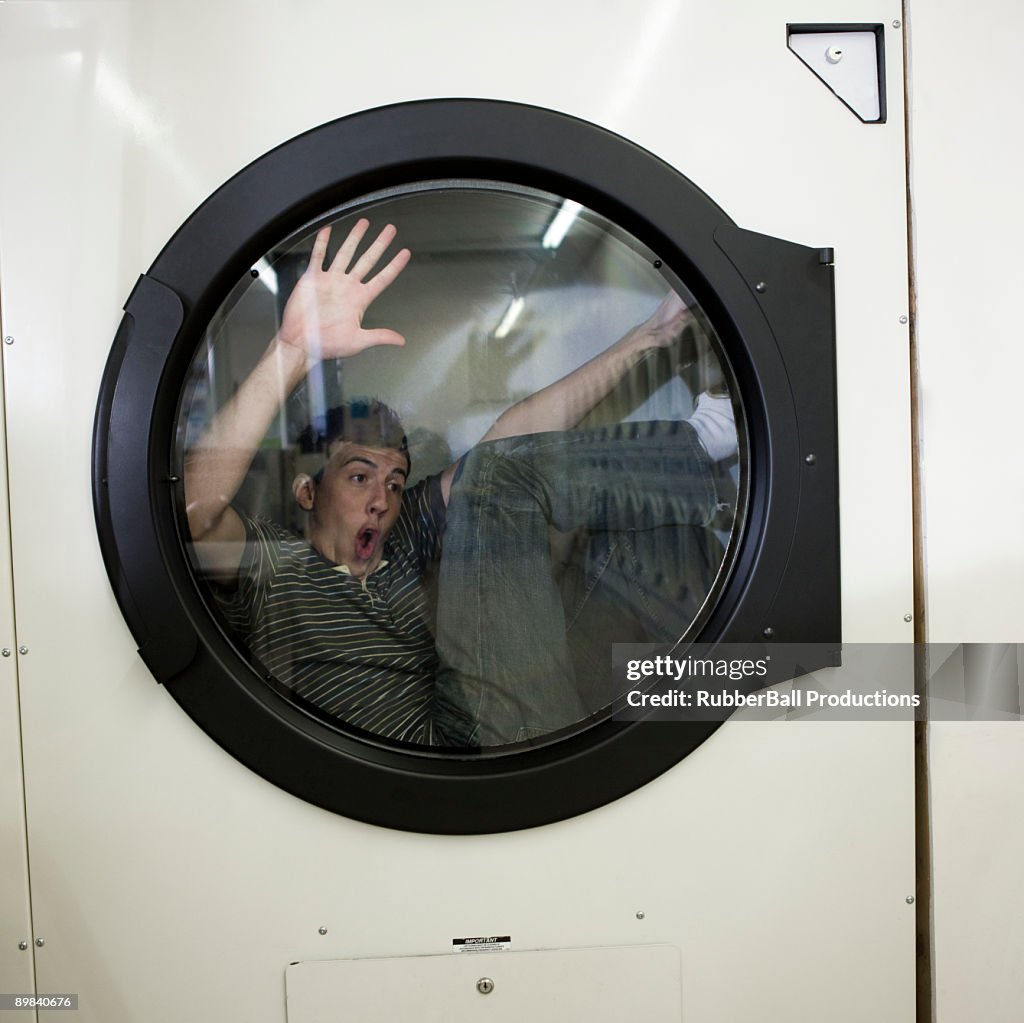 Man inside a commercial clothes dryer at a laundromat