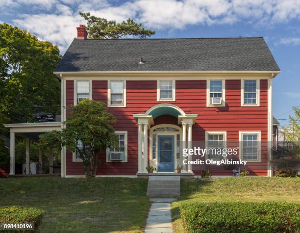 house with red clapboard exterior, green trees, shrubs and blue sky, nyack, rockland county, hudson valley, new york. - blue house red door stock pictures, royalty-free photos & images