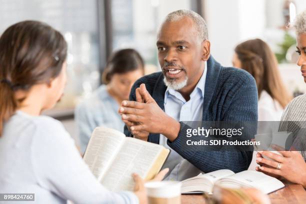 confident senior man studies the bible with friends - senior spirituality stock pictures, royalty-free photos & images