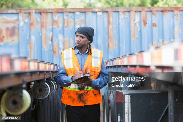 Trabajador con portapapeles, entre dos semi-camiones