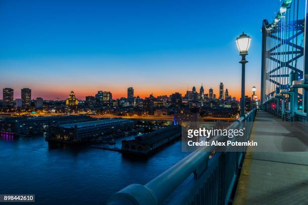 philadelpia downtown at sunset. the view from the benjamin franklin bridge over the piers in old city and delaware river. - philadelphia pennsylvania stock pictures, royalty-free photos & images