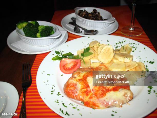 chicken parmigiana served with scalloped potatoes, and side dishes of steamed broccoli and fried mushrooms - chicken parmigiana stockfoto's en -beelden