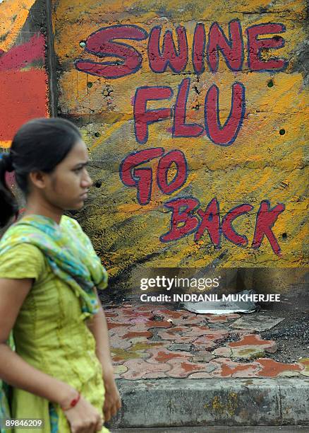 Pedestrian walks past a swine flu grafitti on a wall in Mumbai on August 18, 2009. Thousands of school and colleges are shut down in India's...