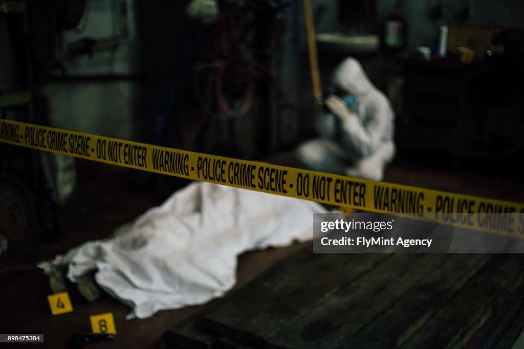 Crime scene investigation - forensic investigating behind dead cover body and evidence