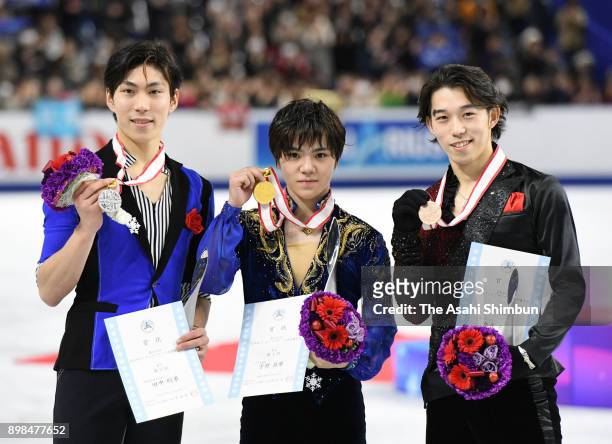 Silver medalist Keiji Tanaka, gold medalist Shoma Uno and bronze medalist Takahito Mura pose for photographs on the podium at the medal ceremony for...
