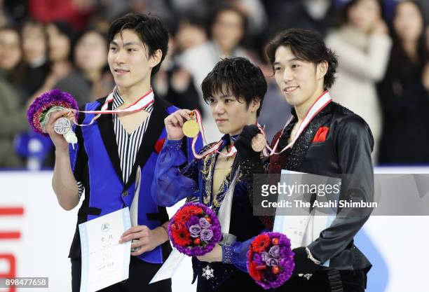 Silver medalist Keiji Tanaka, gold medalist Shoma Uno and bronze medalist Takahito Mura pose for photographs on the podium at the medal ceremony for...