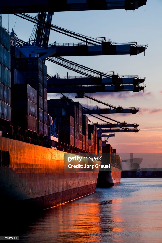 Cargo ships in container terminal sunset