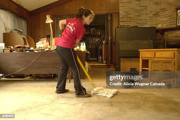 Jessica Tober, 15-years-old, scrubs the floor of her flooded home near Woodlawn Lake July 3, 2002 in San Antonio, Texas. The neighborhood was one of...
