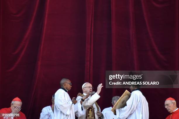 Pope Francis blesses the faithful from the balcony of St Peter's basilica during the traditional "Urbi et Orbi" Christmas address and blessing given...