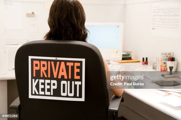 woman at desk with sign on back of chair - keep out sign foto e immagini stock