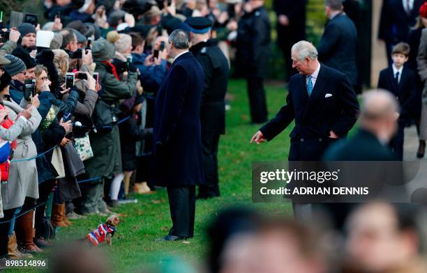 Britain's Prince Charles, Prince of Wales gestures to a small dog held by a well-wisher as he arrives to attend the Royal Family's traditional...