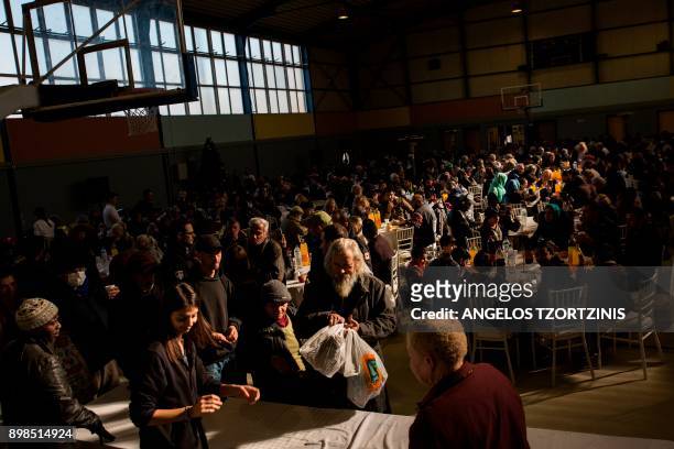 People gather at an indoor basketbal hall as the municipality of Athens organized a Christmas meal for homeless and the poor in Athens on December...