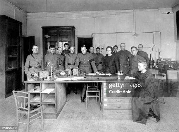Marie Curie , with Irene Curie and men dressed in army uniform in 1919 in the laboratory of Paris university, surrounded by her students, young...