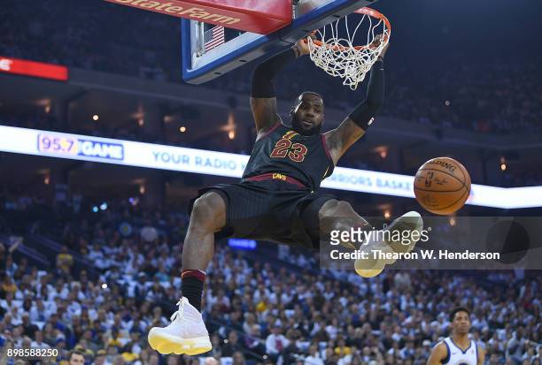 LeBron James of the Cleveland Cavaliers hangs onto the rim after a slam dunk against the Golden State Warriors during an NBA basketball game at...