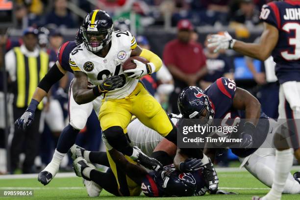 Le'Veon Bell of the Pittsburgh Steelers is tripped up by Zach Cunningham of the Houston Texans and Chunky Clements in the second quarter an at NRG...