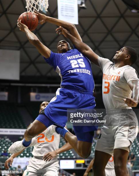 Karl Gamble of the Middle Tennessee Blue Raiders is fouled by Anthony Lawrence II of the Miami Hurricanes as he shoots the ball during the first half...