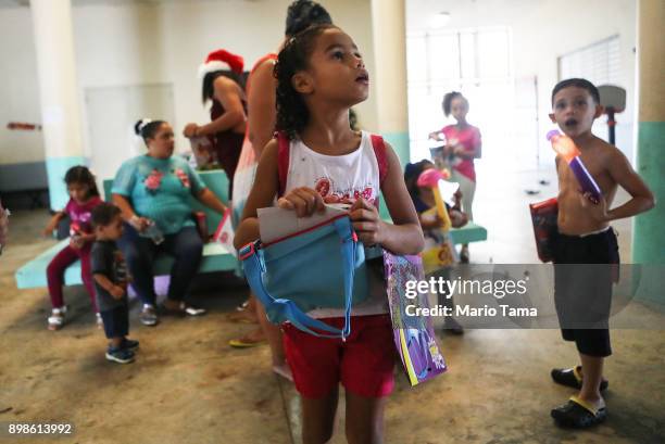 Janellise Rivera , whose family lost their home in Hurricane Maria, waits to receive a Christmas present from a church group in a shelter for...