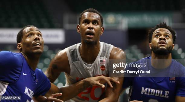 Mike Robinson and Chris Lykes of the Miami Hurricanes battle for position with Dewan Huell of the Miami Hurricanes during a free throw attempt during...