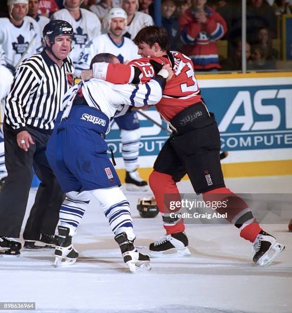 Reid Simpson of the New Jersey Devils battles with Tie Domi of the Toronto Maple Leafs during NHL action on March 6, 1996 at Maple Leaf Gardens in...