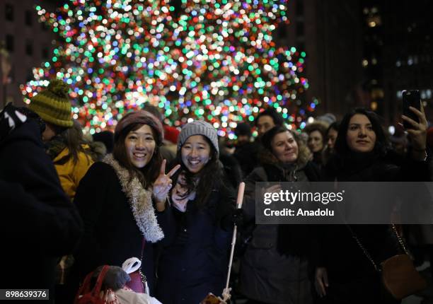 People pose for a photo in front of the illuminated the Christmas tree at Rockefeller Center on on December 26, 2017 in New York City. Christmas tree...