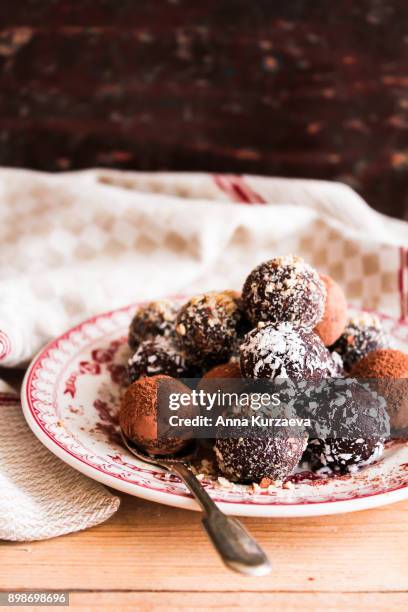 assorted dark chocolate truffles with cocoa powder, homemade biscuits, coconut and chopped hazelnuts on a dessert plate, selective focus - coconut biscuits stockfoto's en -beelden