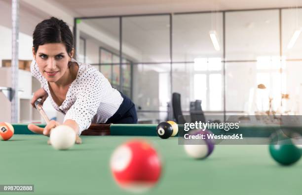 determined businesswoman playing pool billard in modern office - billard tisch stock-fotos und bilder