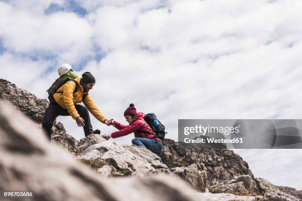 germany, bavaria, oberstdorf, man helping woman climbing up rock - meta turistica fotografías e imágenes de stock
