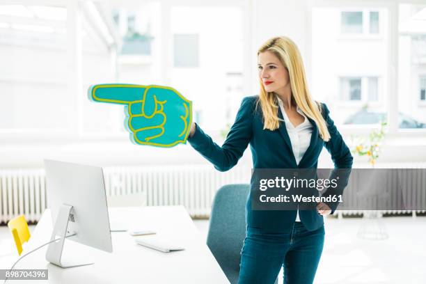confident businesswoman pointing with large hand in office - autoaffermazione foto e immagini stock