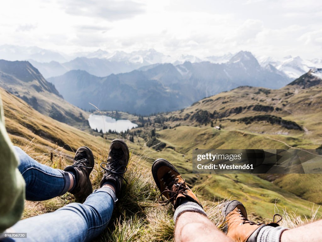Germany, Bavaria, Oberstdorf, legs of two hikers resting in alpine scenery