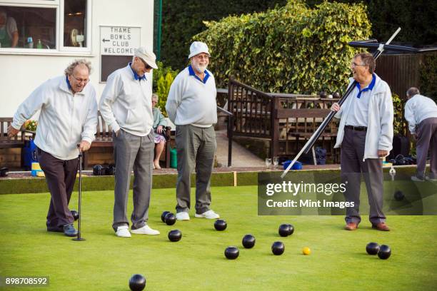 four men on the lawn bowls green, one wearing an umpires coat, at an end. - bowling for buddies stock pictures, royalty-free photos & images