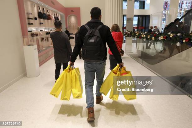 Shopper carries bags during the Boxing Day holiday sales at the Selfridges Ltd. Department store in central London, U.K., on Tuesday, Dec. 26, 2017....