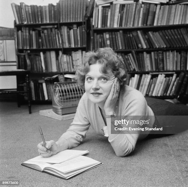 Scottish-born novelist Muriel Spark makes notes while lying on the floor, 25th May 1960.