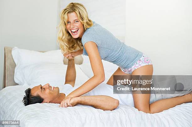 laughing young couple playing and fighting on bed - rough housing stock-fotos und bilder