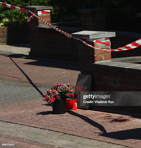 Flowers, candels and a message saying 'Why?' is seen next to the blood marking in front of the crime scene on August 19, 2009 in Schwalmtal near...