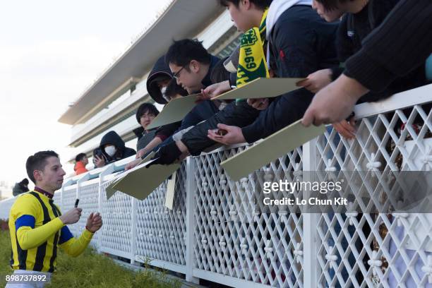 Jockey Cristian Demuro gives his autograph to Japanese racing fans after winning the Race 5 at Hanshin Racecourse on December 17, 2017 in Takarazuka,...