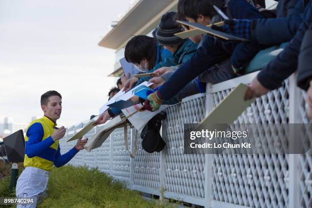 Jockey Cristian Demuro gives his autograph to Japanese racing fans after winning the Race 6 at Hanshin Racecourse on December 17, 2017 in Takarazuka,...