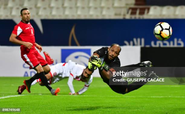 Yemen's goalkeeper and captain Mohammed Ayash leaps to save the ball after it was kicked by Bahrain's forward Mahdi Abduljabbar and Yemeni defender...
