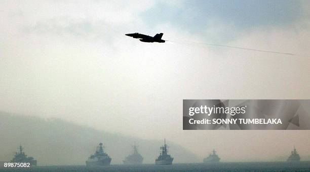 An Indonesian Air Force Sukhoi fighter jet flies past the flotilla of warships participating in the international fleet review in the waters of...