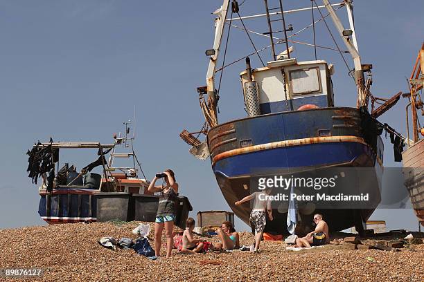 Family enjoy the sun near fishing boats on the sea front on August 19, 2009 in Hastings, England. Parts of the United Kingdom are enjoying some rare...