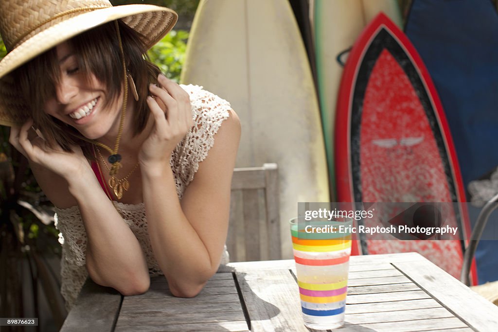 Woman outside leaning on patio table with glass