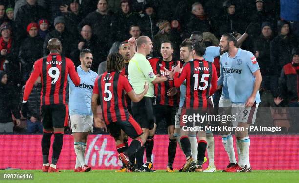 Players from AFC Bournemouth and West Ham United surround match referee Bobby Madley decides weather to allow AFC Bournemouth's third goal during the...