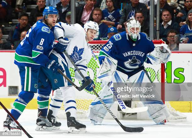 Jacob Markstrom of the Vancouver Canucks looks on as Christopher Tanev of the Vancouver Canucks checks Matt Martin of the Toronto Maple Leafs during...