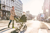 Mother pushing baby stroller on lined pedestrian crossing