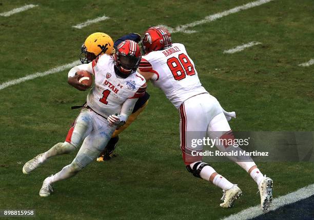 Tyler Huntley of the Utah Utes runs for a touchdown while Harrison Handley of the Utah Utes makes a block on Hakeem Bailey of the West Virginia...