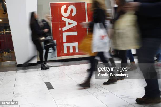 Shoppers walk past a "Sale" sign at the Easton Town Center Mall in Columbus, Ohio, U.S., on Tuesday, Dec. 26, 2017. Americans displayed their buying...