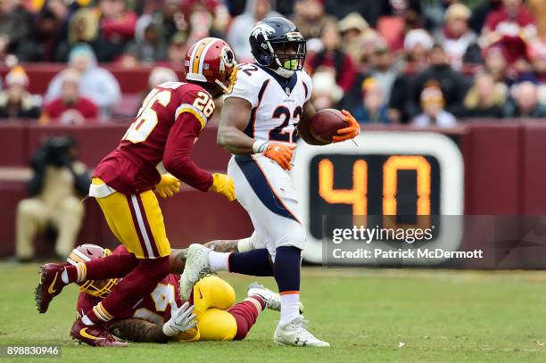 Running back C.J. Anderson of the Denver Broncos runs with the ball past outside linebacker Preston Smith and cornerback Bashaud Breeland of the...